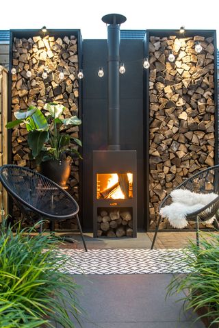 outdoor fireplace with garden chairs either side of it and an outdoor rug