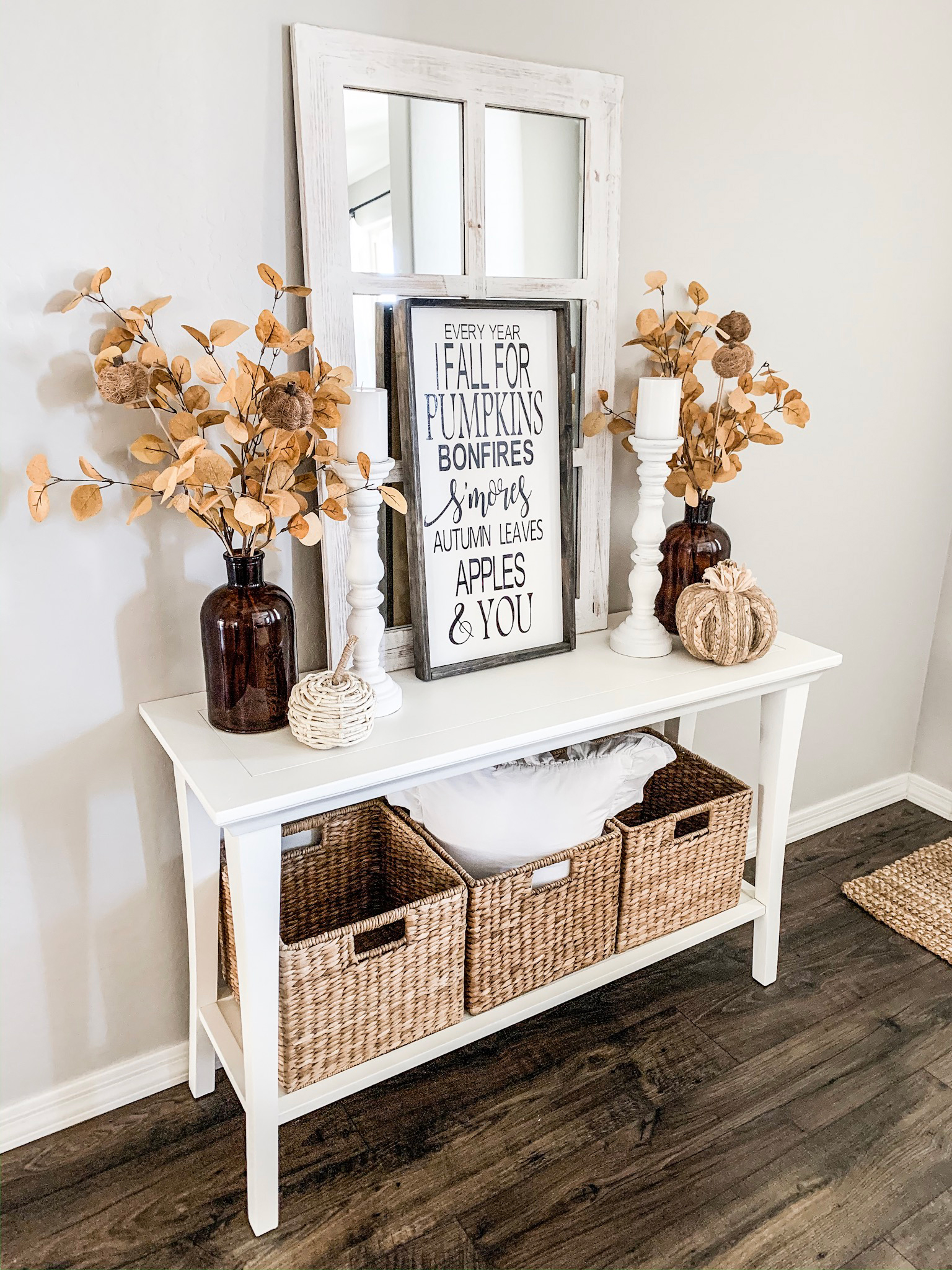 Seasonal console in white entryway decorate with gourds foliage and fall inspired frames