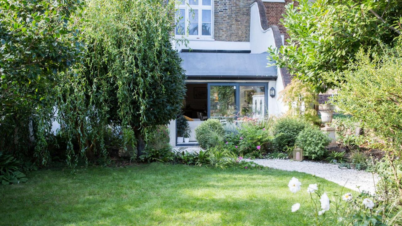 View across the garden to the back of the house with the bi-fold doors open. Garden redesign of a small city garden in London, owned by Rosie Money-Coutts.