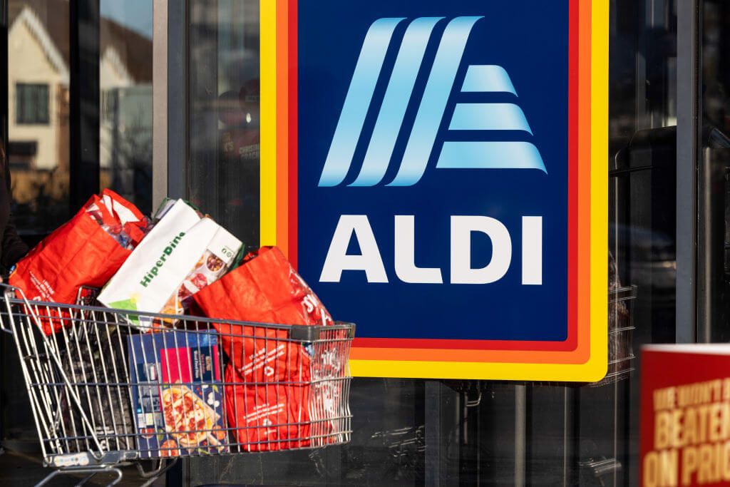 An aldi store with a shopping cart in front filled with groceries