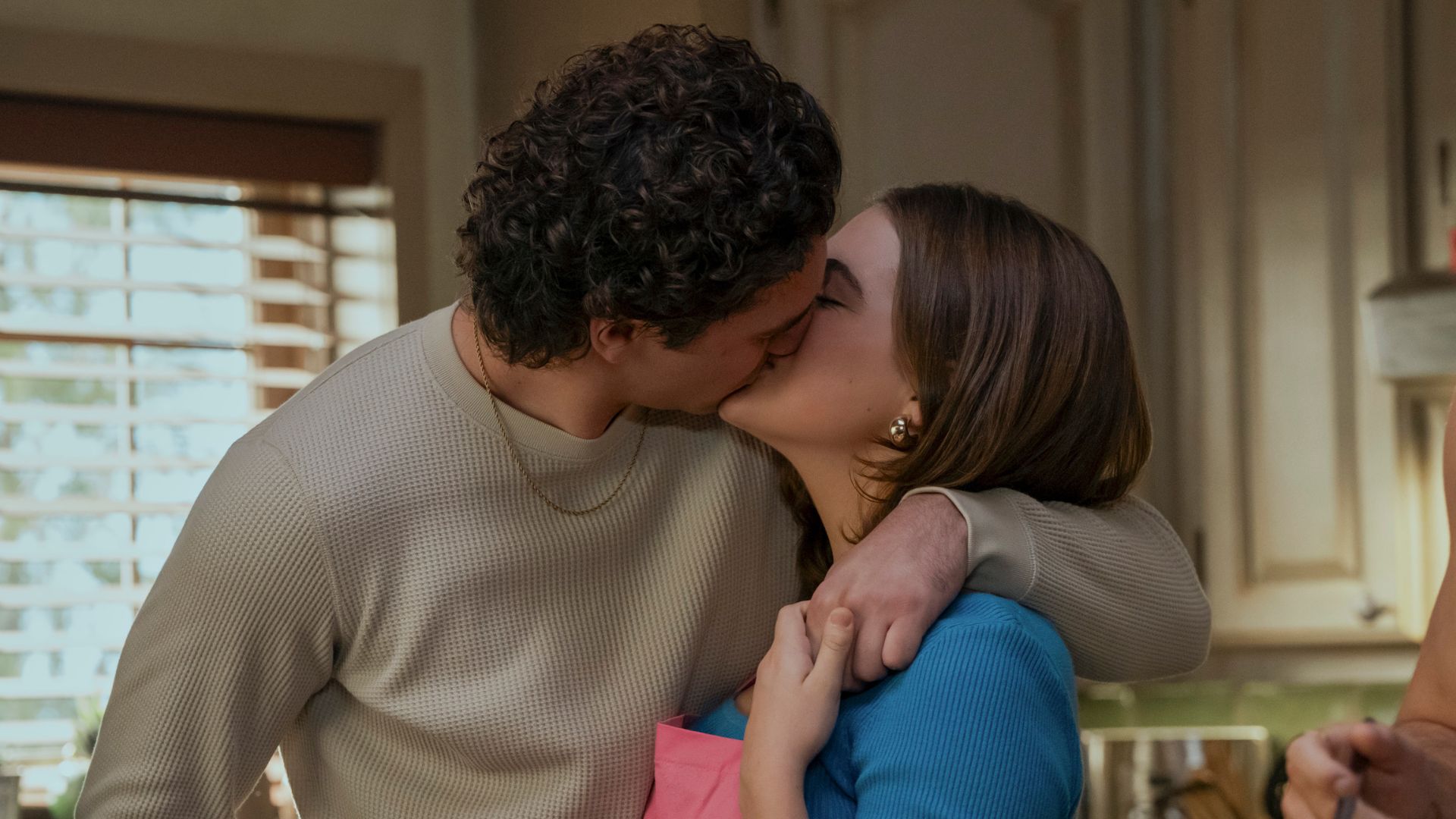 A young couple kiss in a kitchen