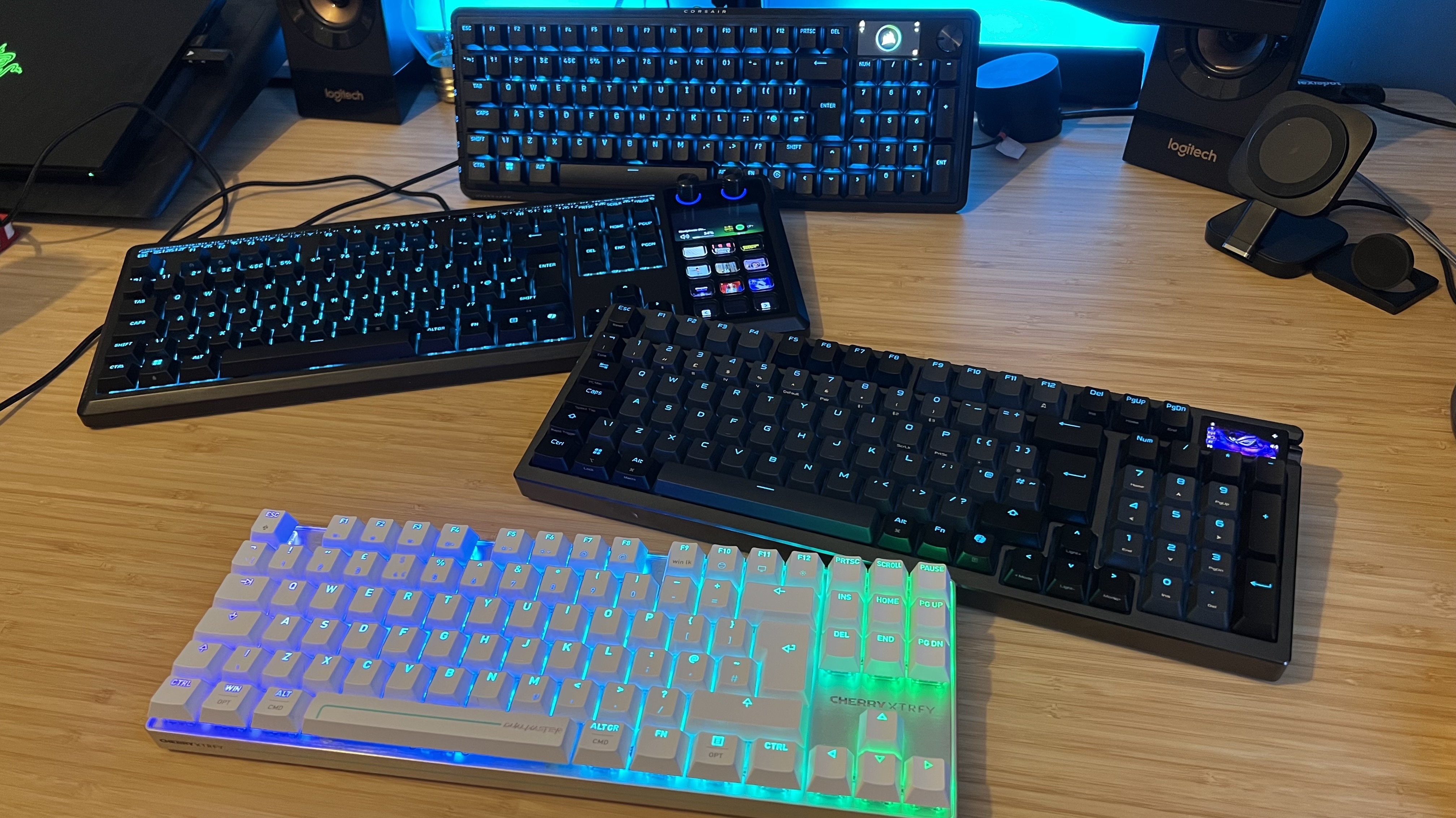 Corsair Vanguard Pro 96, Asus ROG Azoth 96 HE, Corsair Galleon 100 SD and Cherry MX 8.2 Pro TMR TKL on a wooden desk