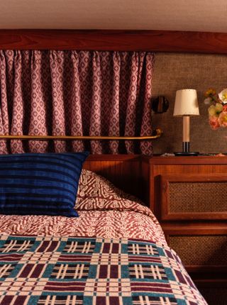 Bedroom with red and blue quilt, dark red and pink curtains and deep blue cushion