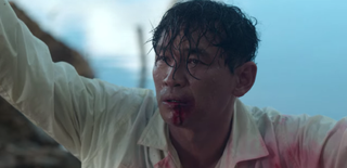 Jeon Yo-hwan covered in blood with his hands raised