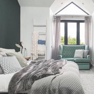 Bedroom with a large bay window and window seat, double bed and feature dark blue green wall. Pub Orig. A four bedroomed modern house in Bishop's Stortford, Hertfordshire, home of Pippa Jamieson, interior designer, her husband Stuart Edwards and two daughters.