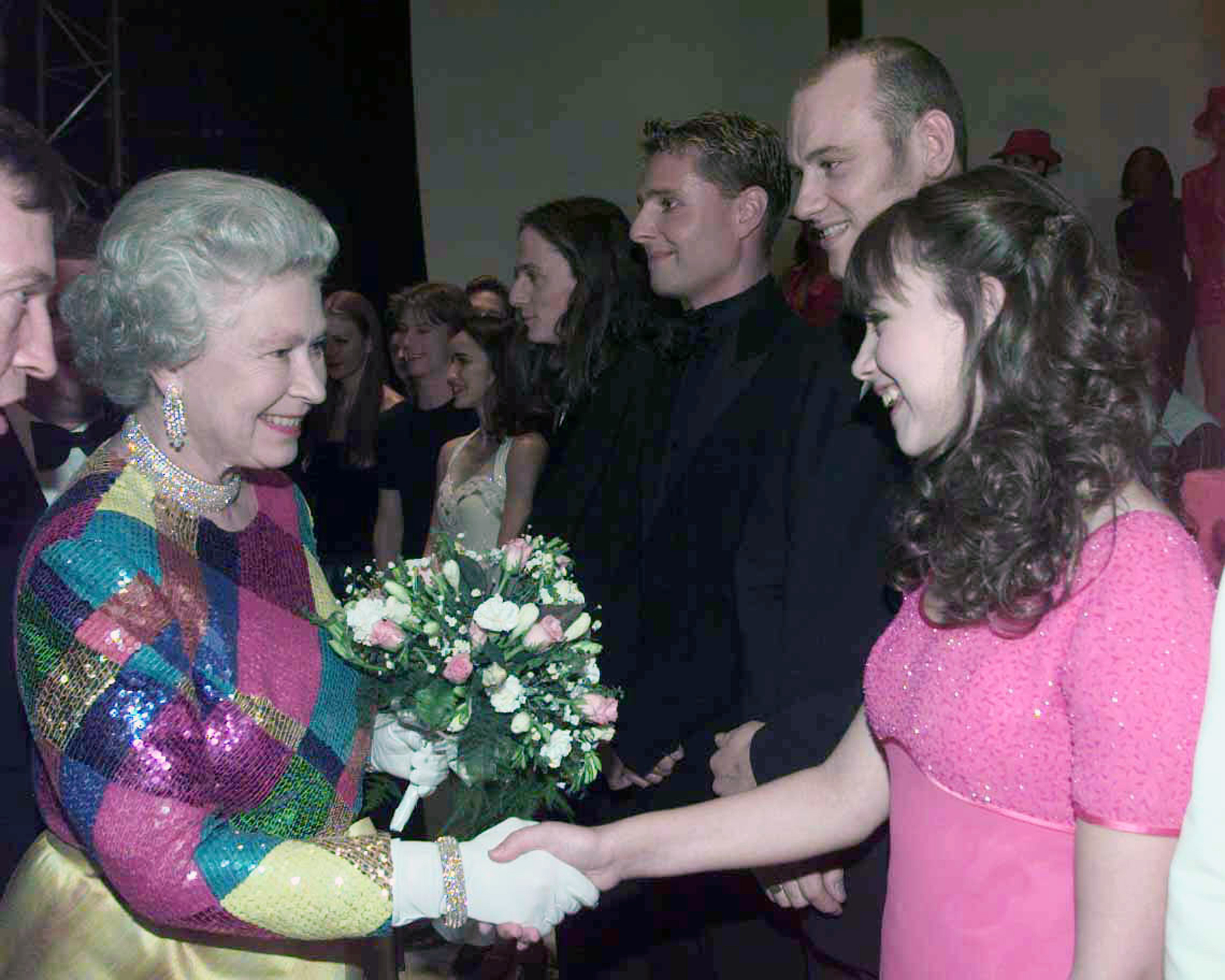 Queen Elizabeth wearing a sequin harlequin dress shaking hands with Charlotte Church