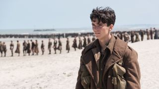 Fionn Whitehead as Tommy Jensen stands on the beach with other troops in Dunkirk
