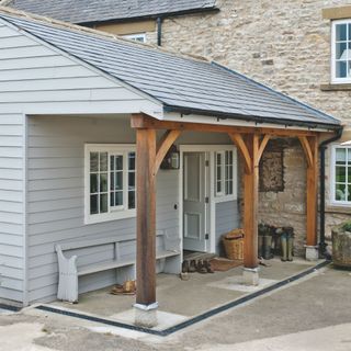 Cladded extension of a cottage, with wooden beams and a front door