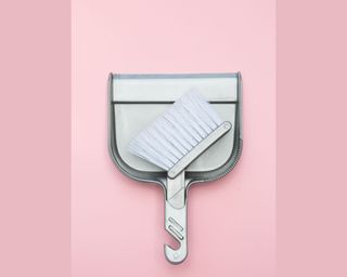 A pink two tone background with a dustpan and brush