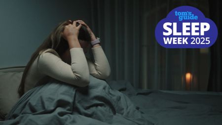 A woman sat up in bed holding her head in distress after a night terror, with a Tom's Guide Sleep Week 2025 logo in the top right hand corner