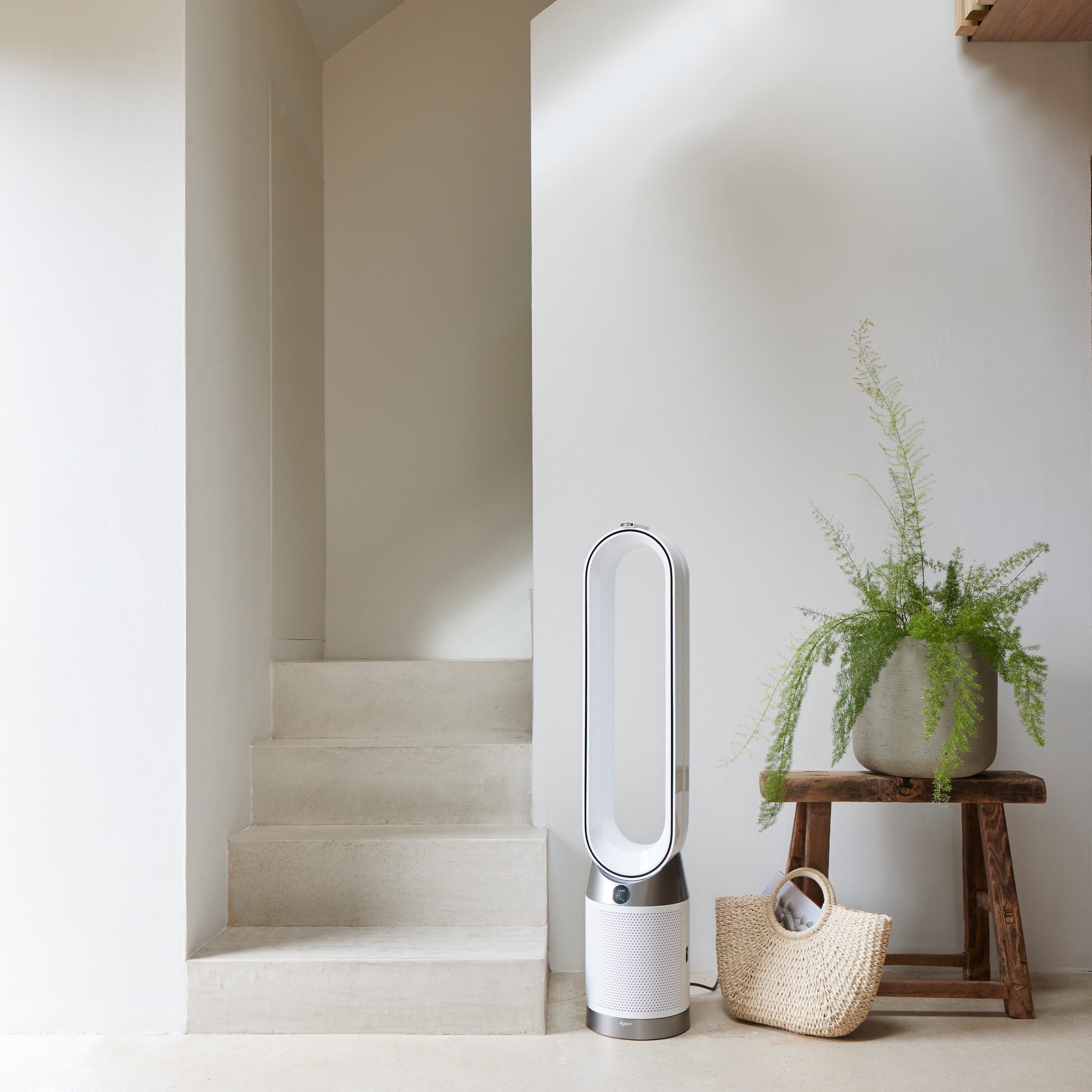 Dyson Purifier Cool PC1 in a white hallway with side table, plant and raffia bag