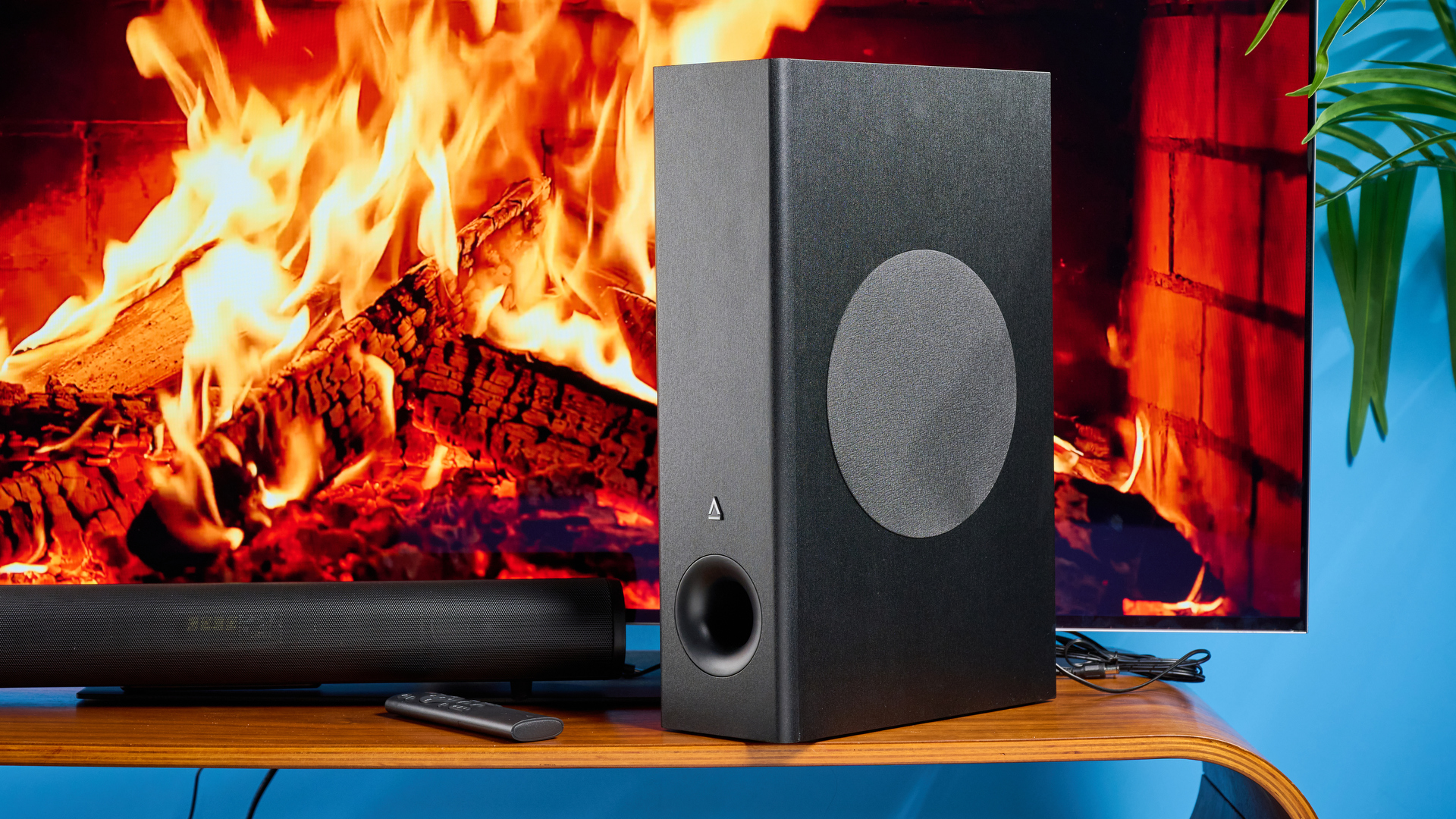 the creative stage pro soundbar and subwoofer, a super-budget home cinema system with 2.1 channels and a remote control photographed on a wooden tv stand with a TV behind