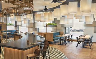 Dining area with a curved bar, geometric floor tiles, parquet flooring and numerous large white lightshades