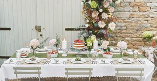 garden party table with cottage garden flowers and a strawberry print tablecloth