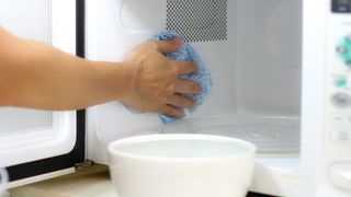 Using a cloth to clean a microwave oven in kitchen room