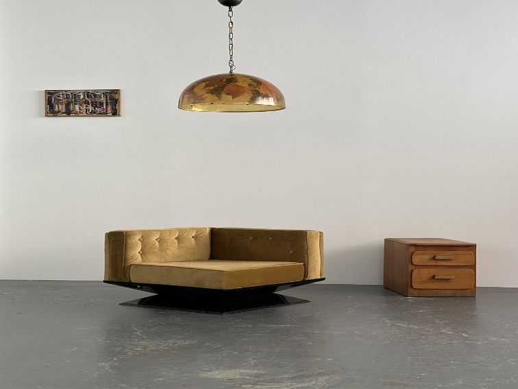 In an industrial gallery, a series of modern furniture items including sofas, sculptural maps, mirrors and wooden chairs create a timeless atmosphere.