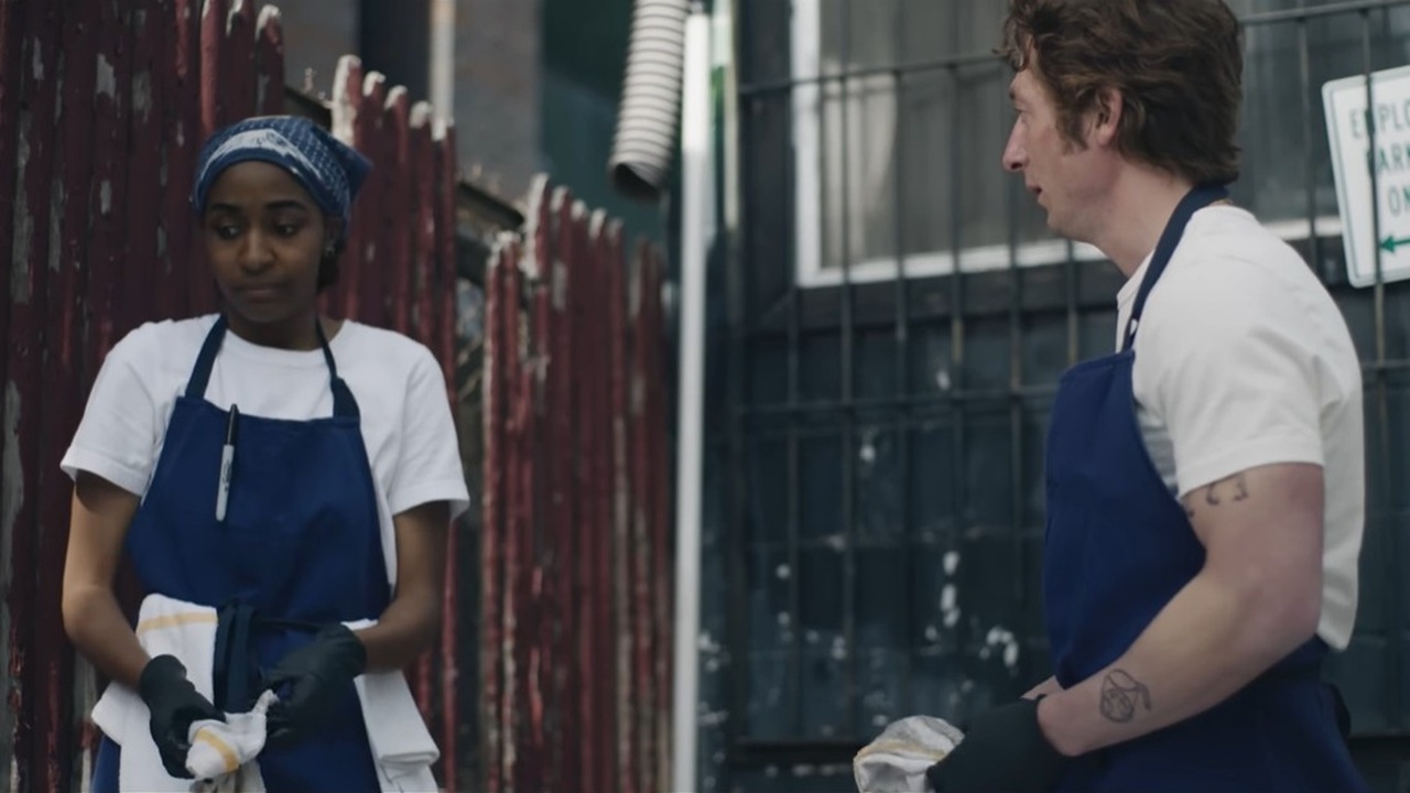 Chef Carmy (Jeremy Allen White) and sous-chef Sydney (Ayo Edebiri) in blue aprons, as the former tries to persuade her he&#039;ll change the chaotic way The Bear as they stand in a nearby alleyway in The Bear Season 4.