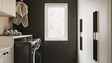 a utility room with a dark feature wall, built in cabinets and black laundry appliances