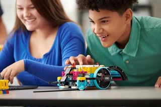 Smiling middle school boy and girl play with Lego robot