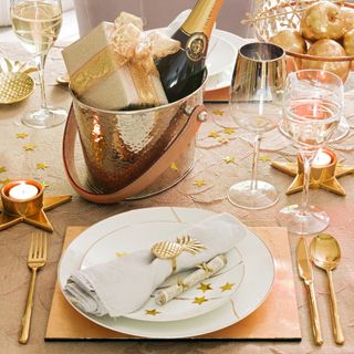 A dining table set for New Year's celebrations with golden decor and star-shaped confetti