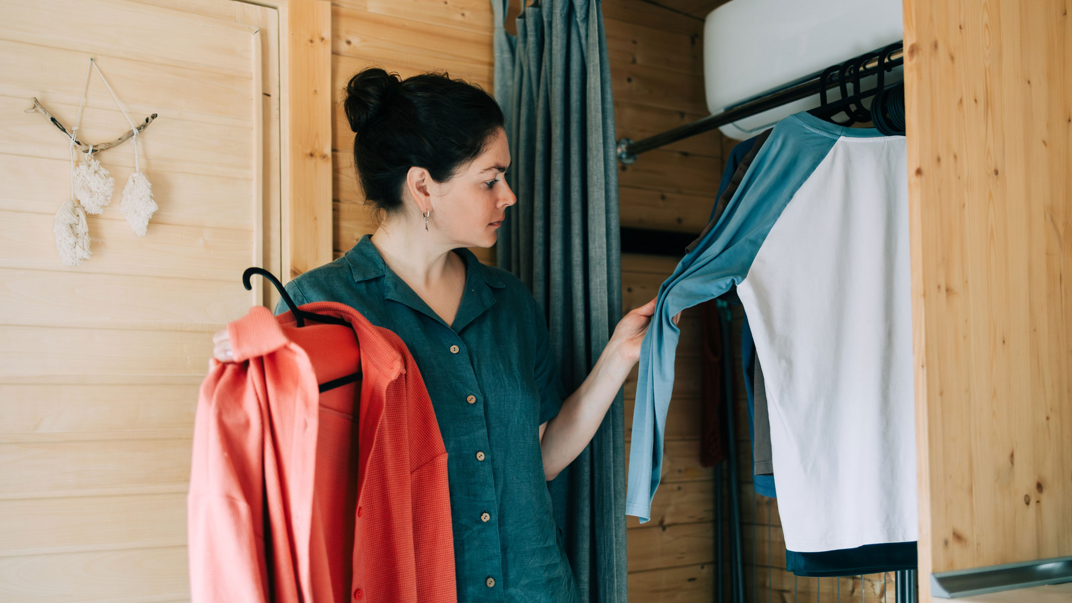 A woman picking a shirt in front of an open closet