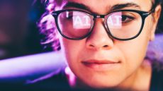 An employee uses AI at work, and the letters "AI" are reflected in her glasses.