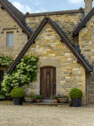 Exterior of the front of the Cotswold stone cottage with the gravel drive in the foreground