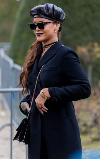 Rihanna wearing Dior sunglasses, navy coat, beret outside Dior on March 3, 2017 in Paris, France.