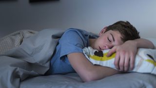 Young teenage boy asleep in bed