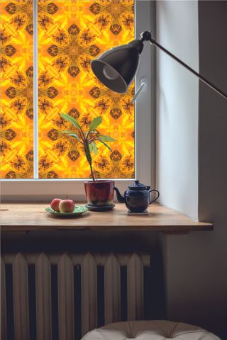 Amber window film with floral pattern, with wooden table window sill and lamp
