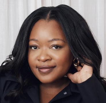 a black woman with long dark curls and gold earrings smiling at the camera