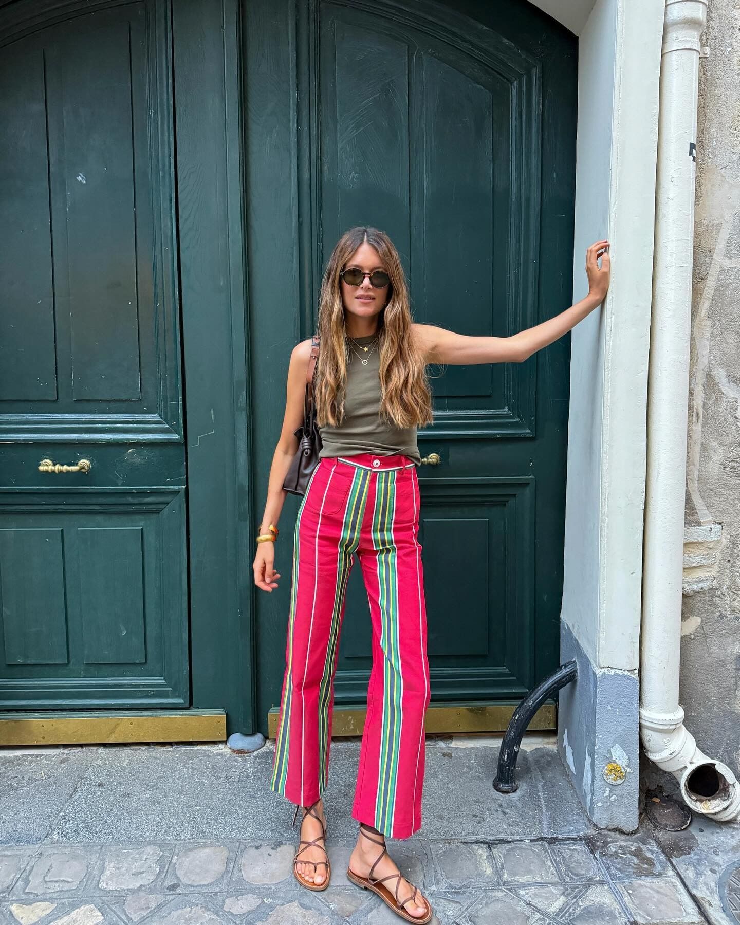 Influencer Sara wears red and green striped cotton pants from La Veste with a green tank and brown sandals.