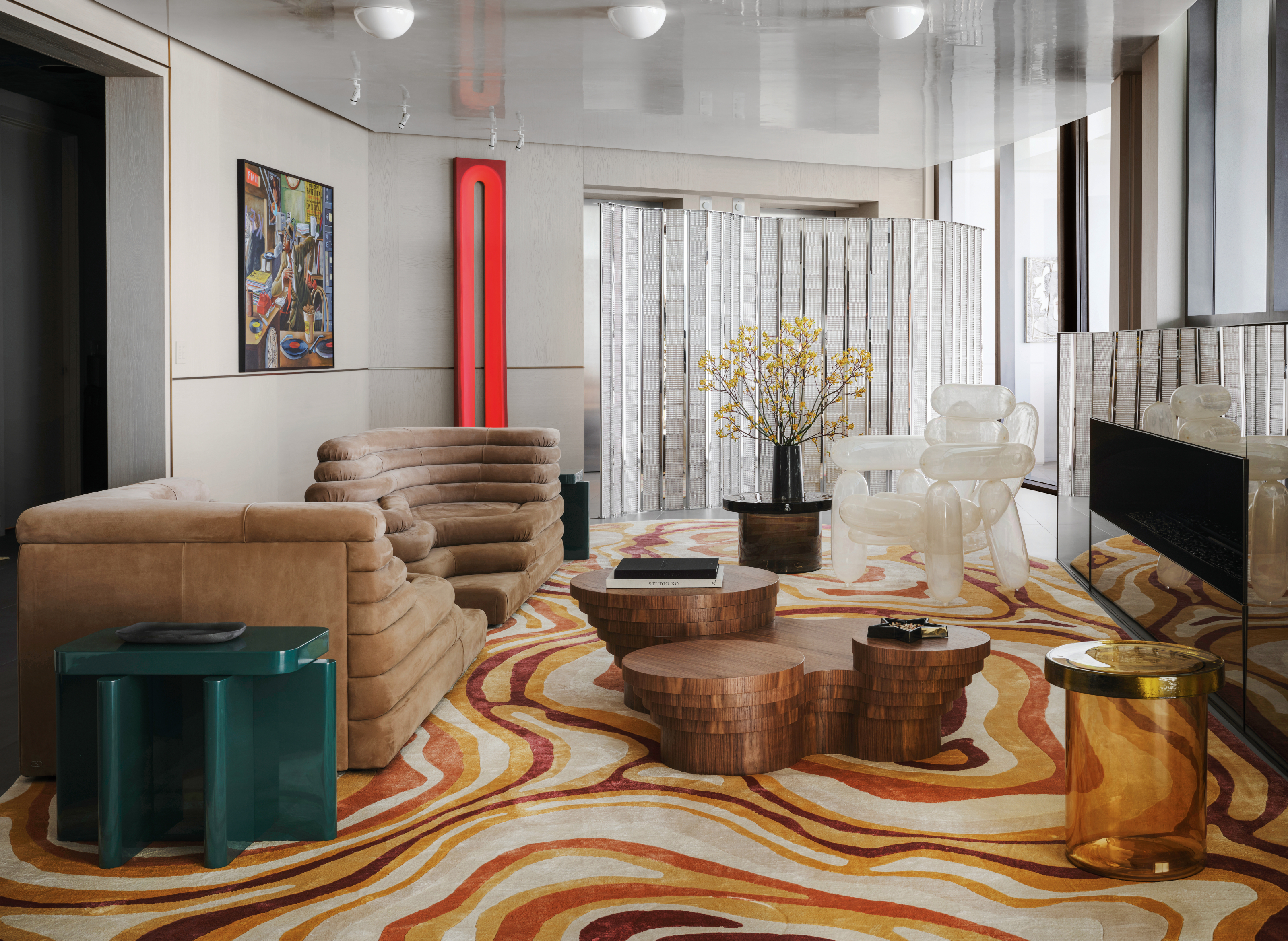 Living room with swirly 70s-style silk rug, Terrezza sofa in brown leather, wood coffee table, inflatable-effect white armchair and mirrored fireplace