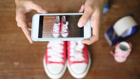 Online seller taking a photo of a pair of shoes to upload online