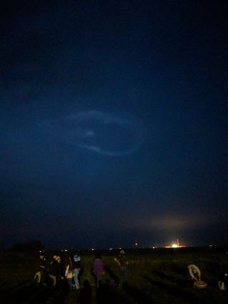 You can see the aftermath of the Antares launch, a still-brightly lit launch pad and a vibrant blue cloud ring.
