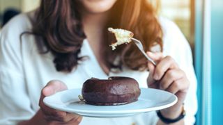 image shows a woman eating a chocolate covered donut
