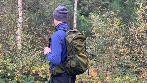 Hiker wearing the Osprey Talon Earth 22 backpack