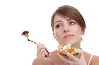 A tired woman eats a salad