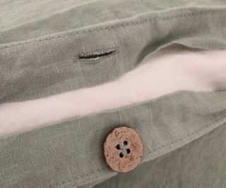 Close up on the buttons on the Piglet in Bed Sage Green Bedding Bundle.