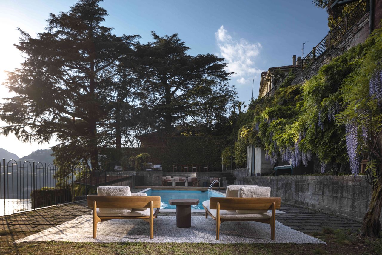 Two wooden sunbeds and a small table at the side of an outdoor pool