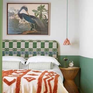 Green and white bedroom with green patterned headboard and red pattern blanket