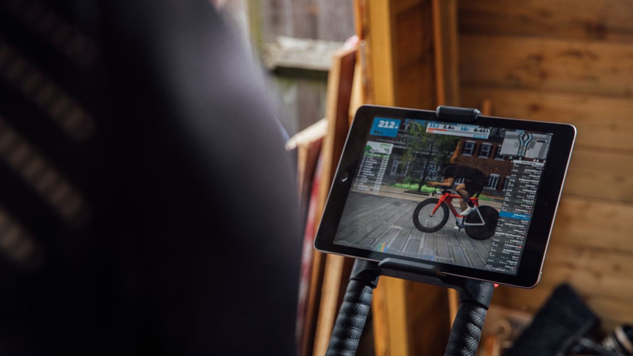 Image over the back of a rider&#039;s shoulder showing iPad with a Zwift session running