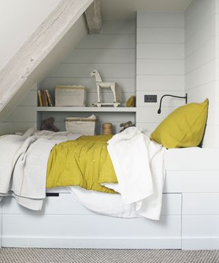White box room ideas featuring a single bed with yellow throw and built-in storage.