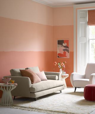 pink living room with 3 shades on noe wall, taupe couch, white boucle armchair, cream rug, white side tables, artwork, pink cushions and vase