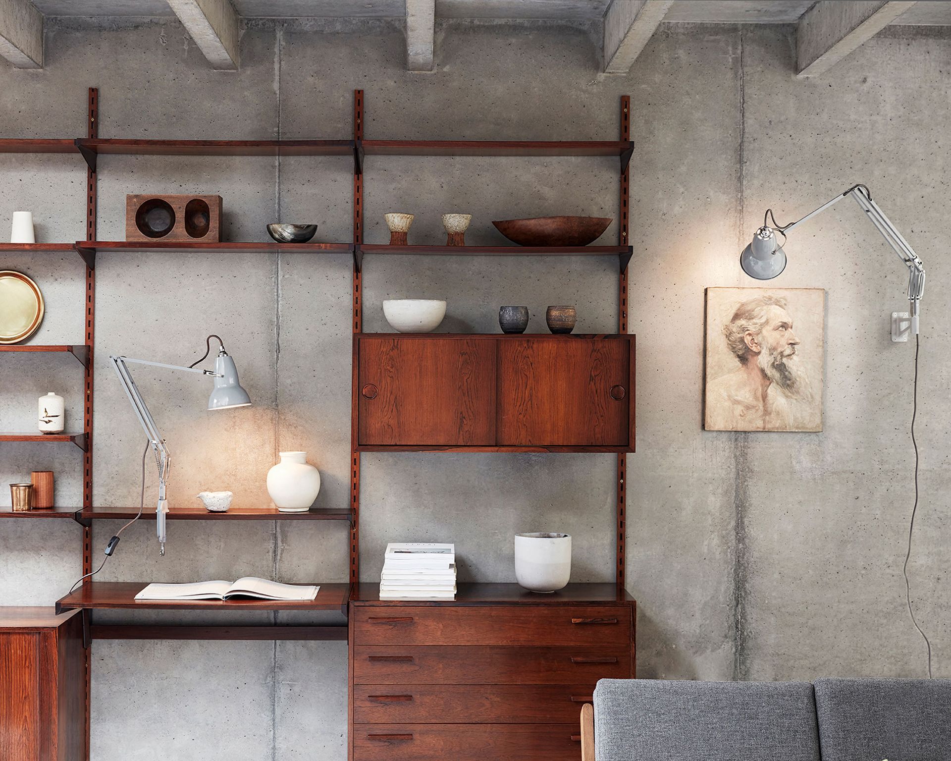Anglepoise lamps providing living room lighting on a grey concrete wall.