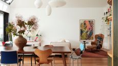 A bright and beautiful summery living room with a dining table, mismatched dining chairs and a trio of pendant paper lanterns