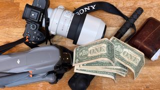 A drone, a Sony Camera, A Insta 360 X4, a wallet and some American dollars