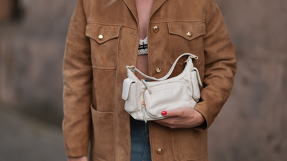 Sonia Lyson seen wearing Miu Miu white / black knit bra, Miu Miu brown suede leather jacket, Miu Miu white leather Pocket bag, Zara blue denim long skirt, on September 03, 2023 in Berlin, Germany. 