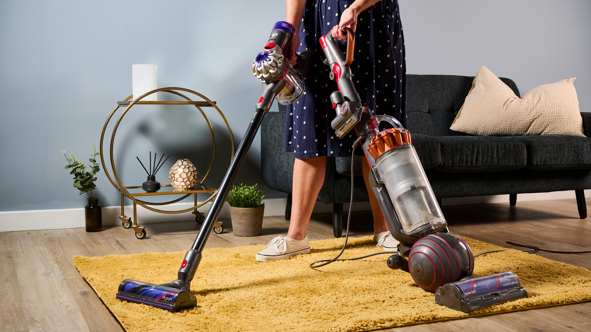 Tester holding Dyson Ball Animal upright vacuum cleaner next to the Dyson V8 to show comparison