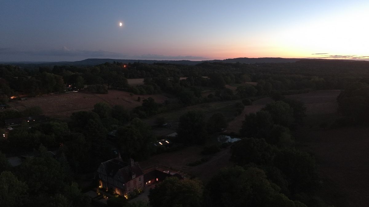 An aerial view of the UK countryside at last light - the moon is out, the sun is setting